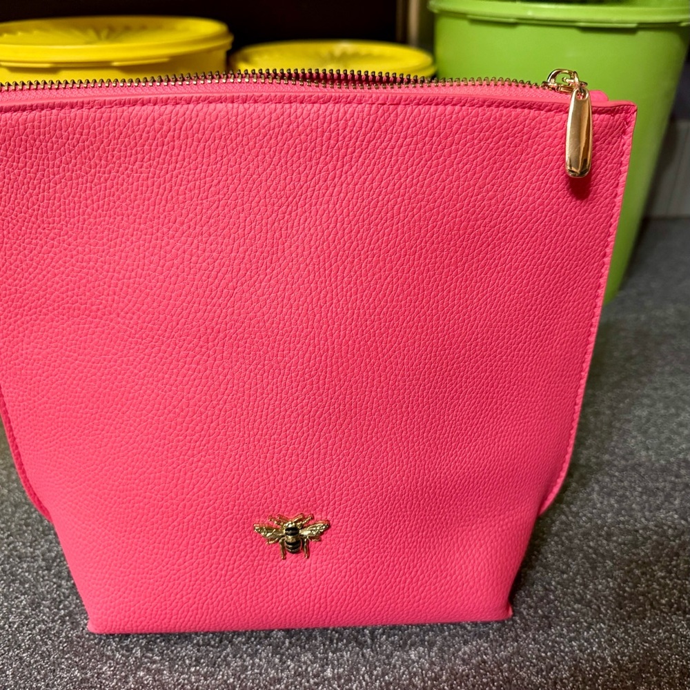Pink cosmetics bag with 🐝 emblem. Has two inside pockets.